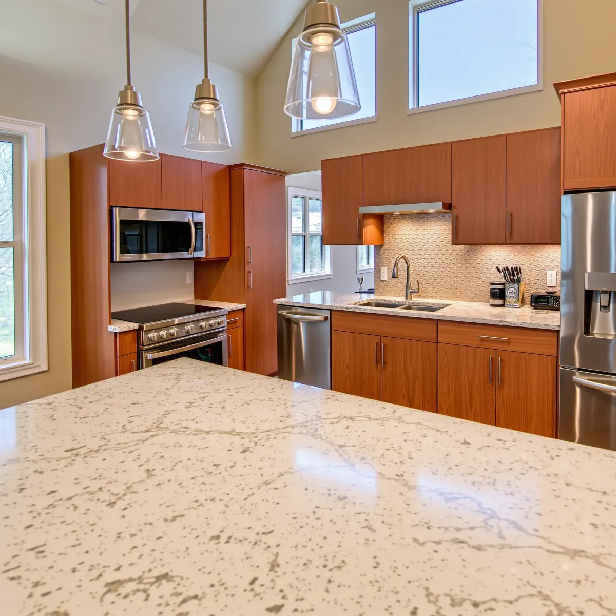 Completed modern kitchen in Rockford, TN with wooden cabinets, stainless appliances, quartz counters, and lush garden view.