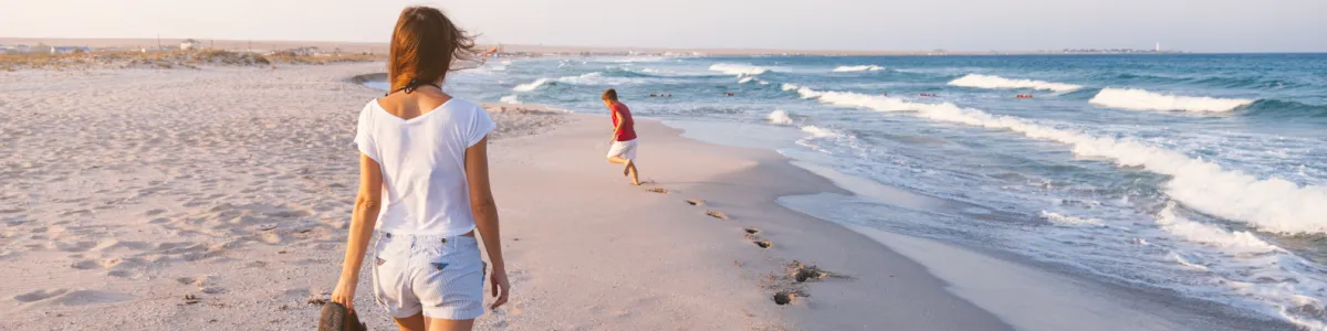 Mother and son walking along sandy beach