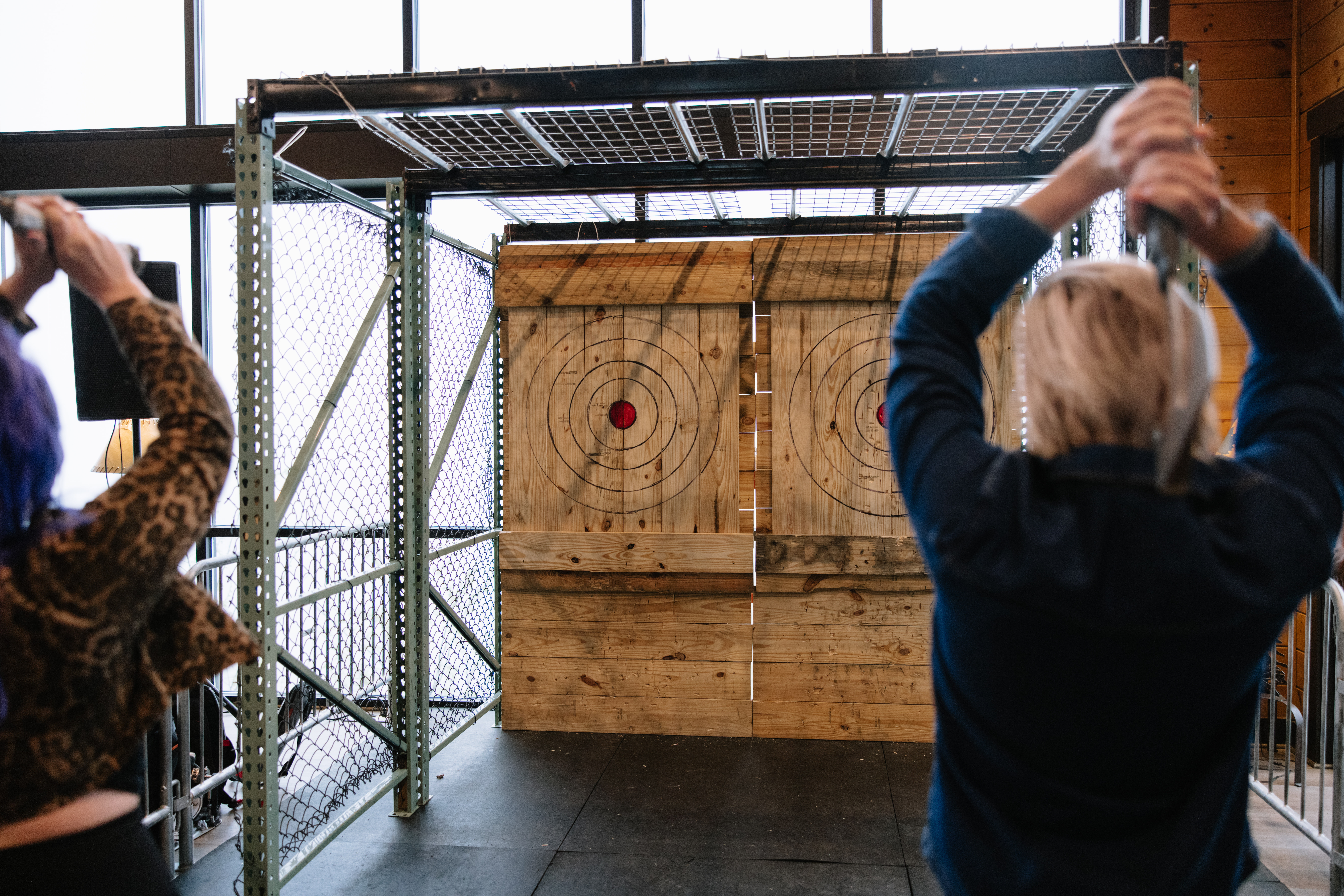 Mobile axe throwing setup with two wooden targets and participants preparing to throw axes indoors, highlighting Edgeway Events' portable axe throwing service.