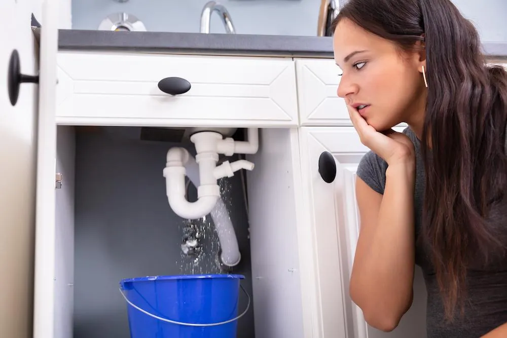 A concerned homeowner looks at a plumbing issue before calling 1Call Plumbing