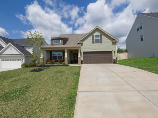 Suburban home with large concrete driveway and blue sky