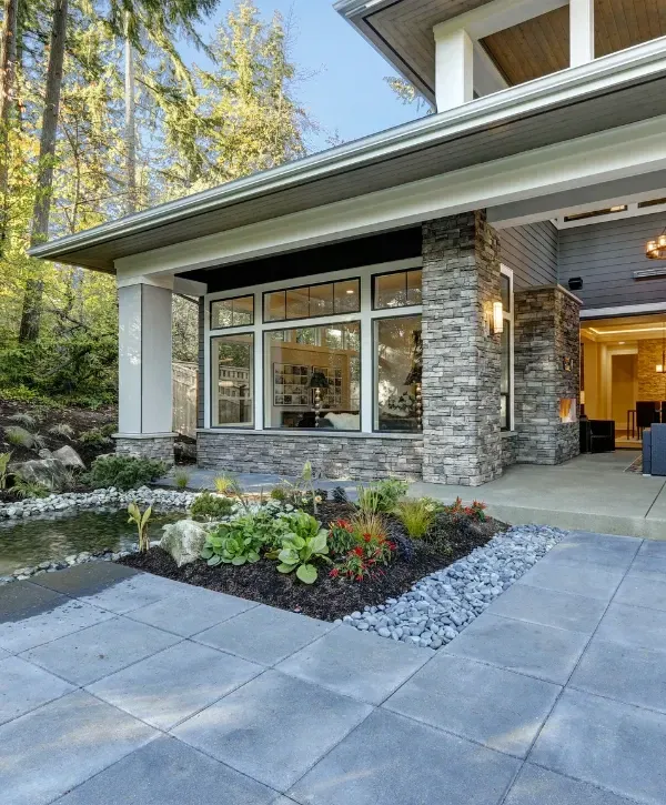 Modern home exterior with stone facade and beautifully landscaped front yard. 