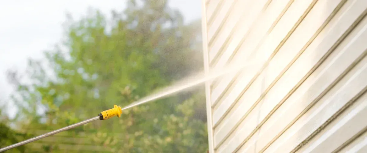 Pressure washing vinyl siding on a house exterior
