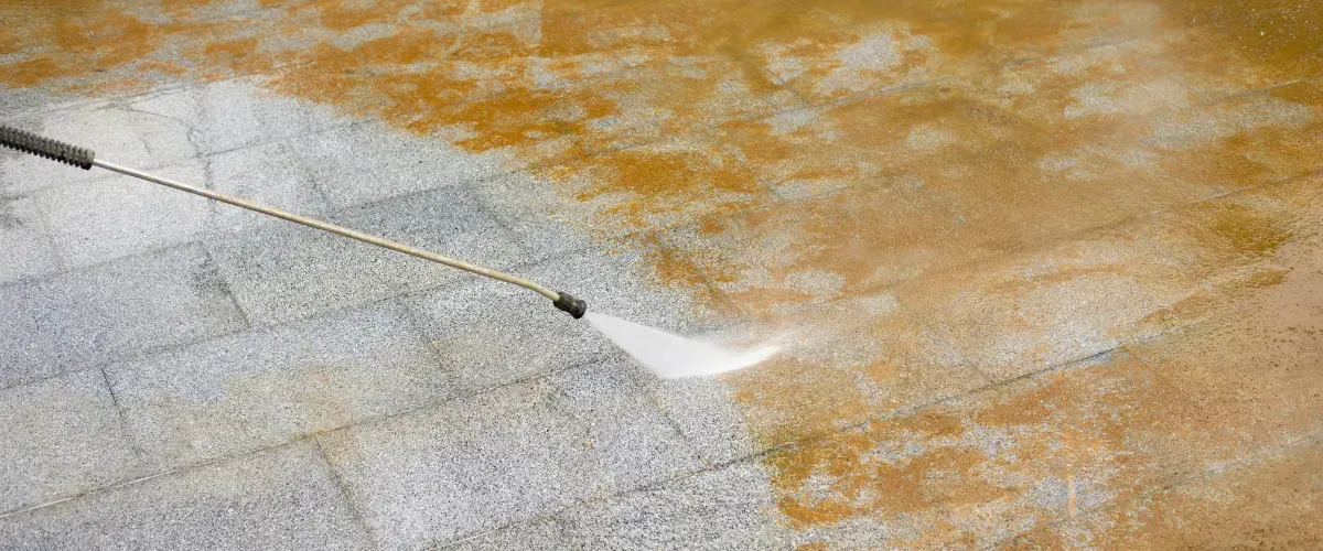 Pressure washer cleaning heavily stained outdoor pavers, removing dirt and buildup.