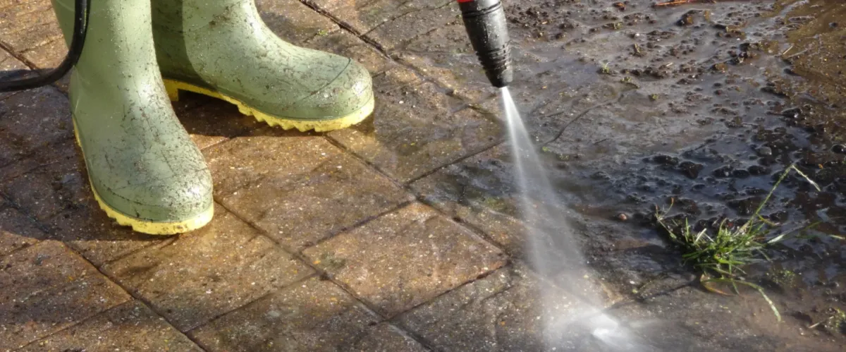 Pressure washing concrete driveway surface to remove grime