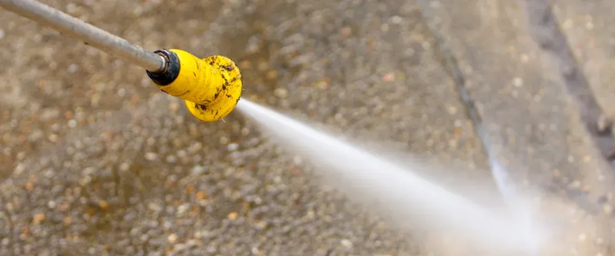 Pressure washer nozzle spraying water onto concrete surface