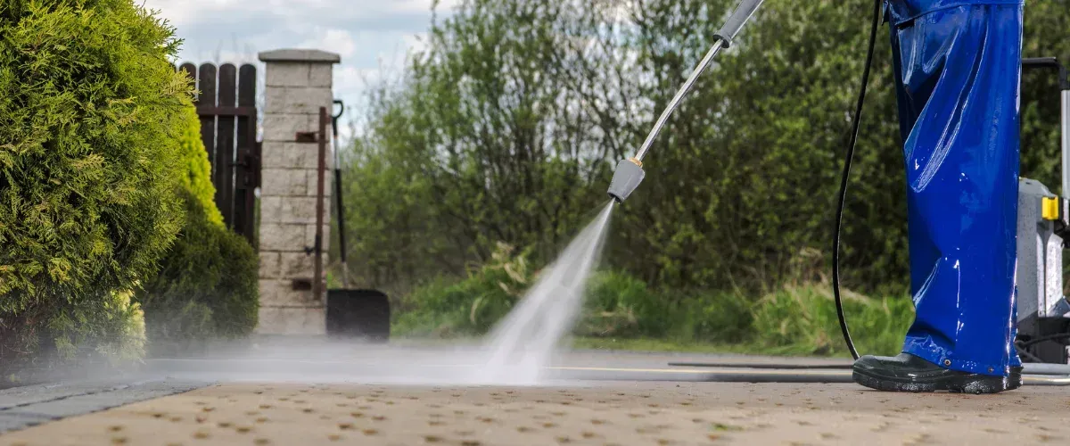 Pressure washing concrete driveway surface to remove grime