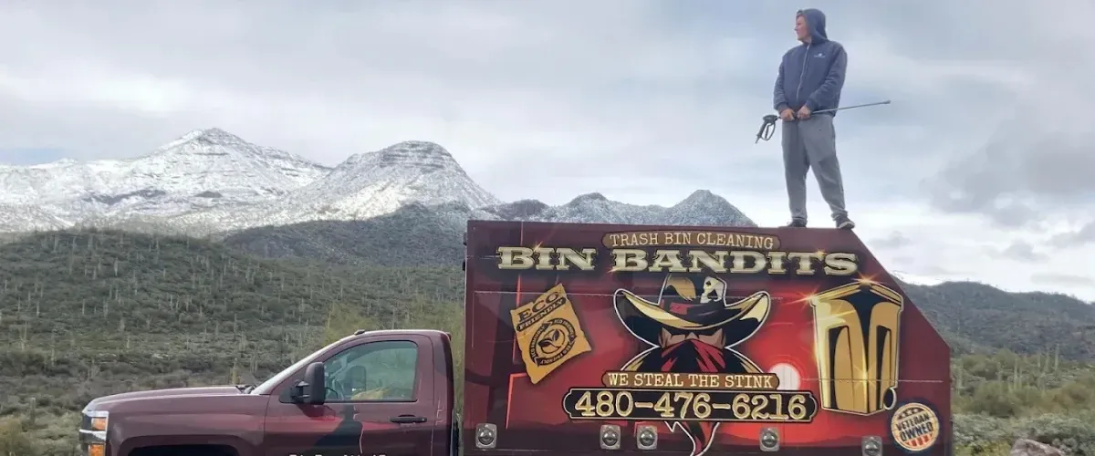 Technician standing on Bin Bandits truck with mountain landscape backdrop