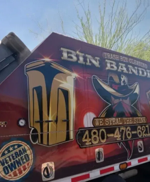 Close-up of the red Bin Bandit trash bin cleaning truck side with 'We Steal The Stink' and phone number.