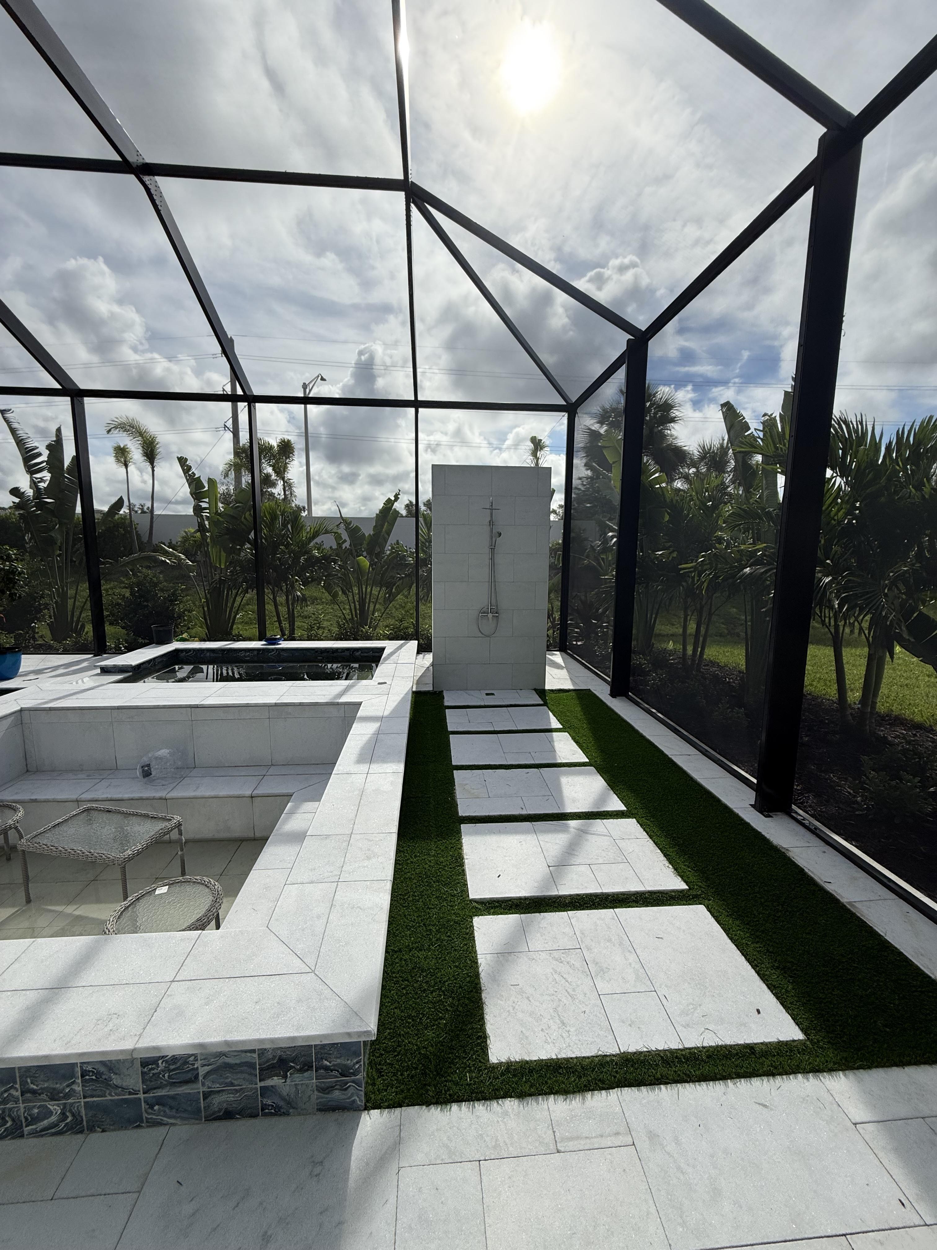 Custom outdoor living oasis featuring a built-in Jacuzzi, integrated indoor-outdoor pool access, and a designer outdoor shower installation by GMS Roofing and Construction LLC.