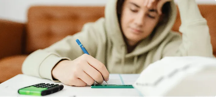 Student focused on homework while using time management and study skills to reduce stress.