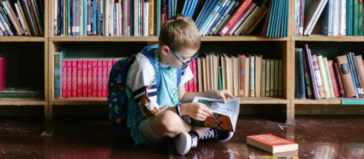 Young child reading a book in a comfortable learning environment to build literacy and comprehension skills.