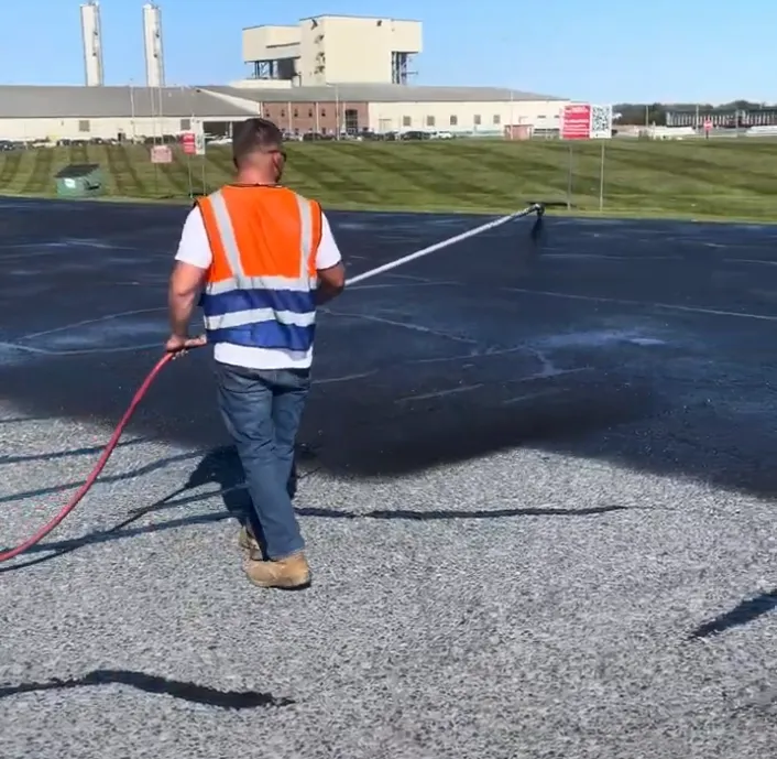 man spraying seal coating on a school parking lot