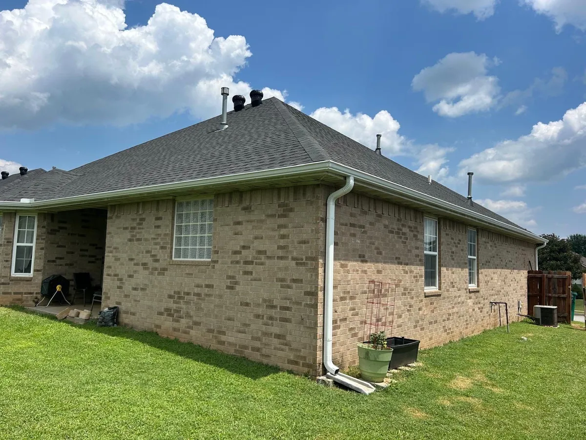 Brick home exterior with asphalt shingle roof and gutters for roof inspection