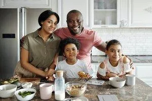 Mother Father and two kids in a kitchen  with breakfast foods