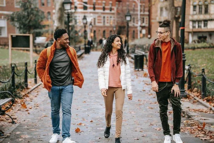 Three people walking down a street in the fall