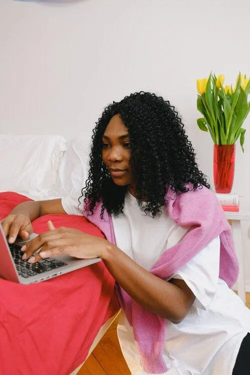 A woman sitting on a bed using a laptop