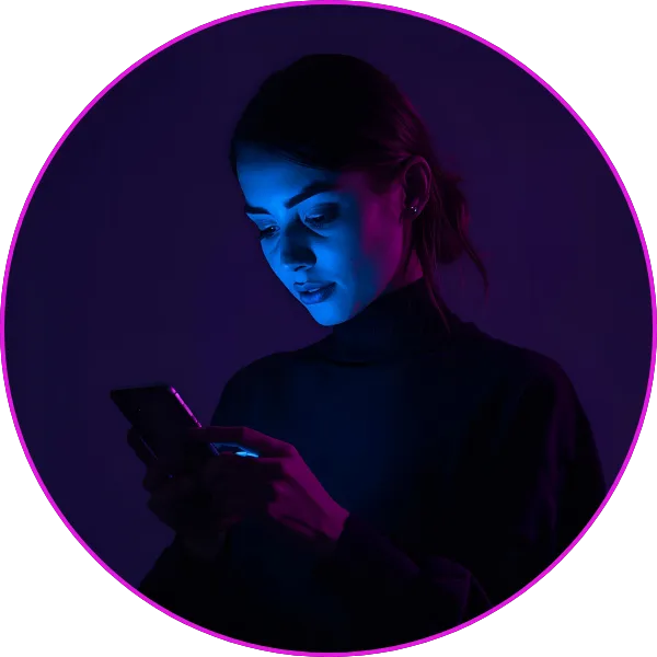 A woman looking down at her smartphone, illuminated by blue and purple neon lighting in a dark environment.