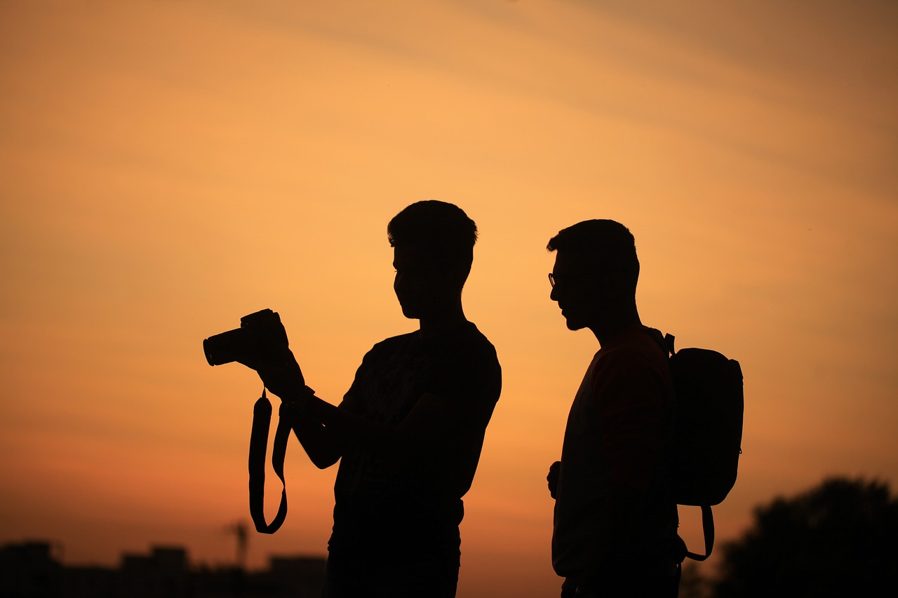 Dark picture of two people. One is holding a camera.