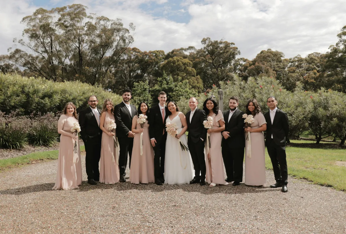 A wedding party in custom made-to-measure wedding outfits at an outdoor venue for their wedding