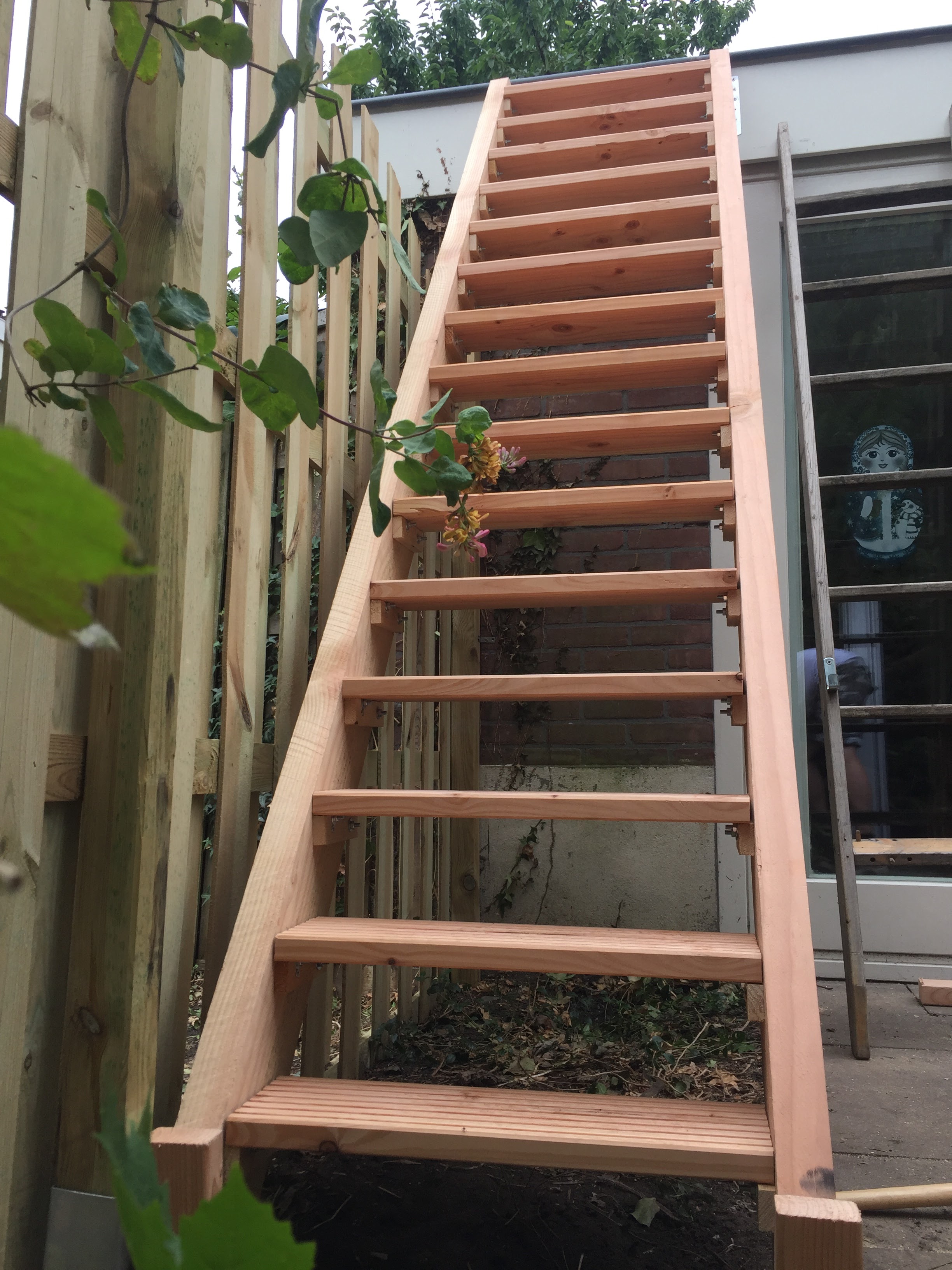 Stevige houten trap op maat gemaakt tussen schuur en uitbouw voor toegang tot dakterras in Zeist.