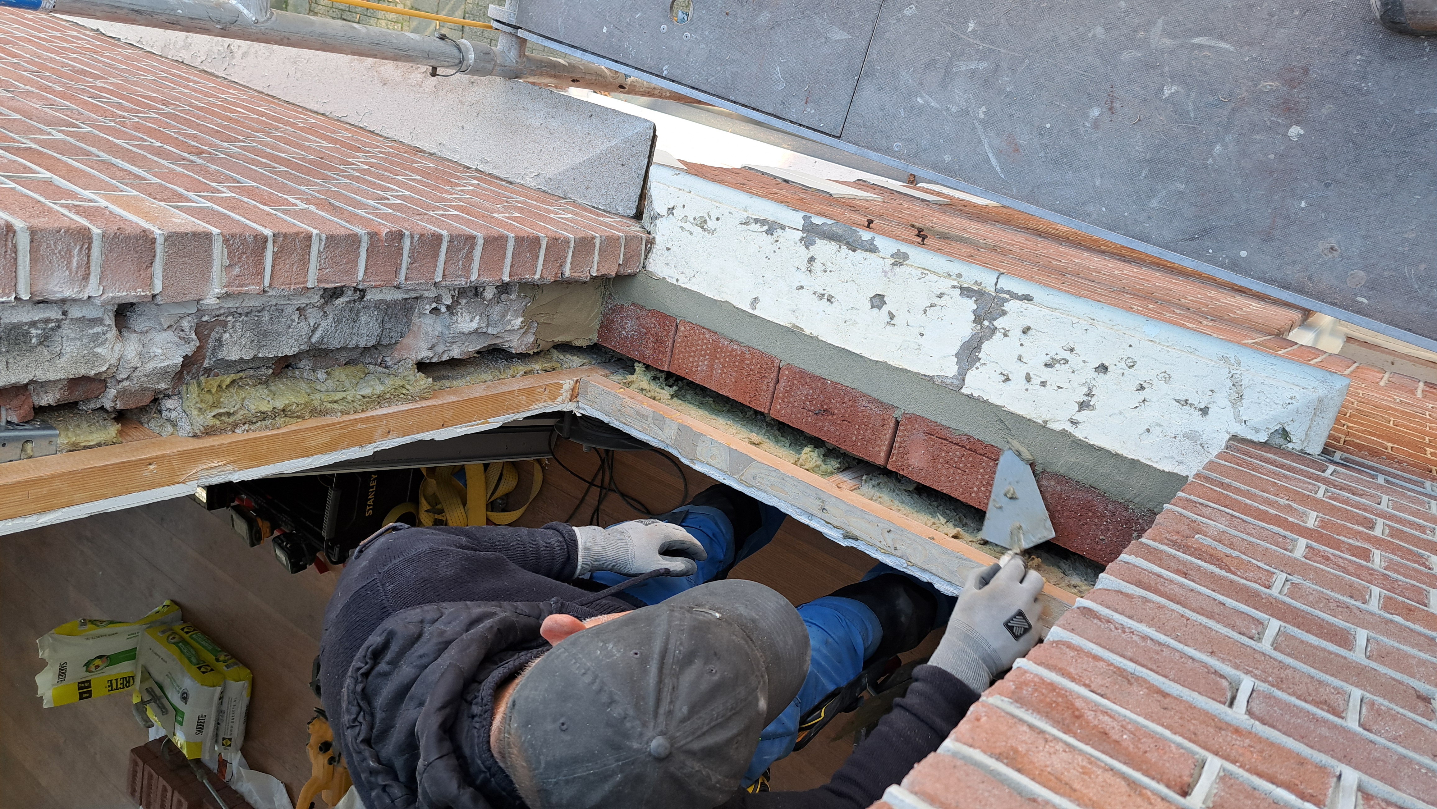 Vakman Tyon van IMT Bouwservice werkt met troffel aan bouwkundig herstel van spouwmetselwerk bij kozijnrenovatie in Veenendaal.