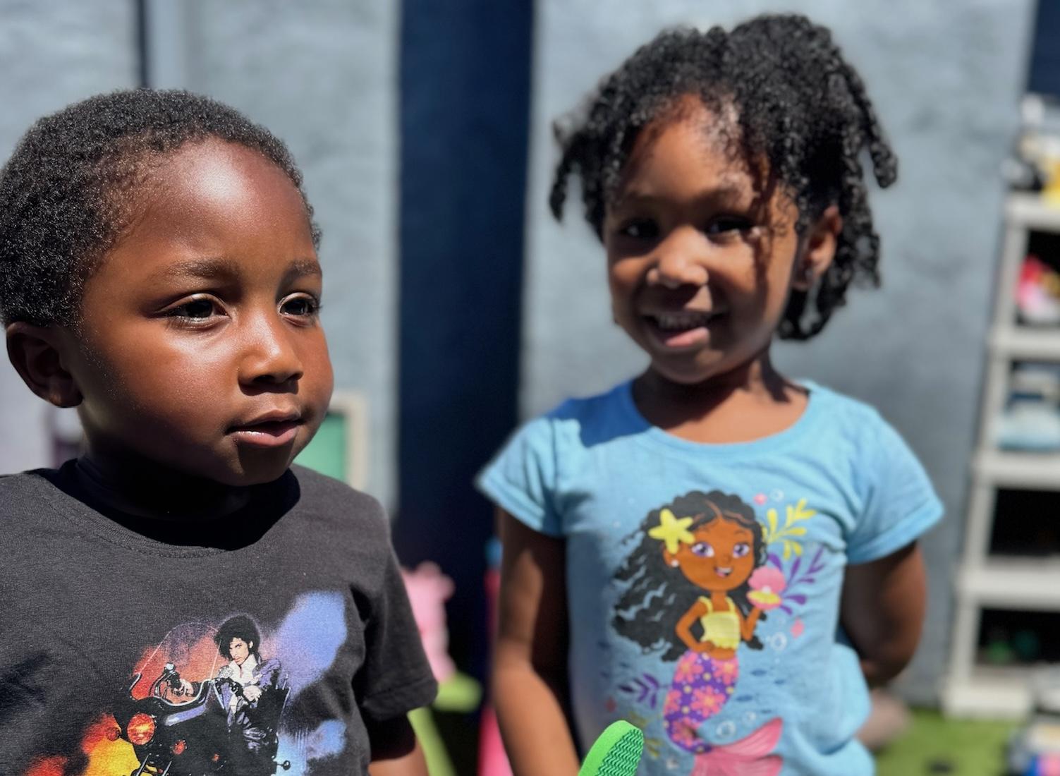 Child with headset smiles as he engages with laptop