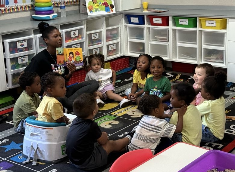 Girl folds paper while watching teacher on laptop