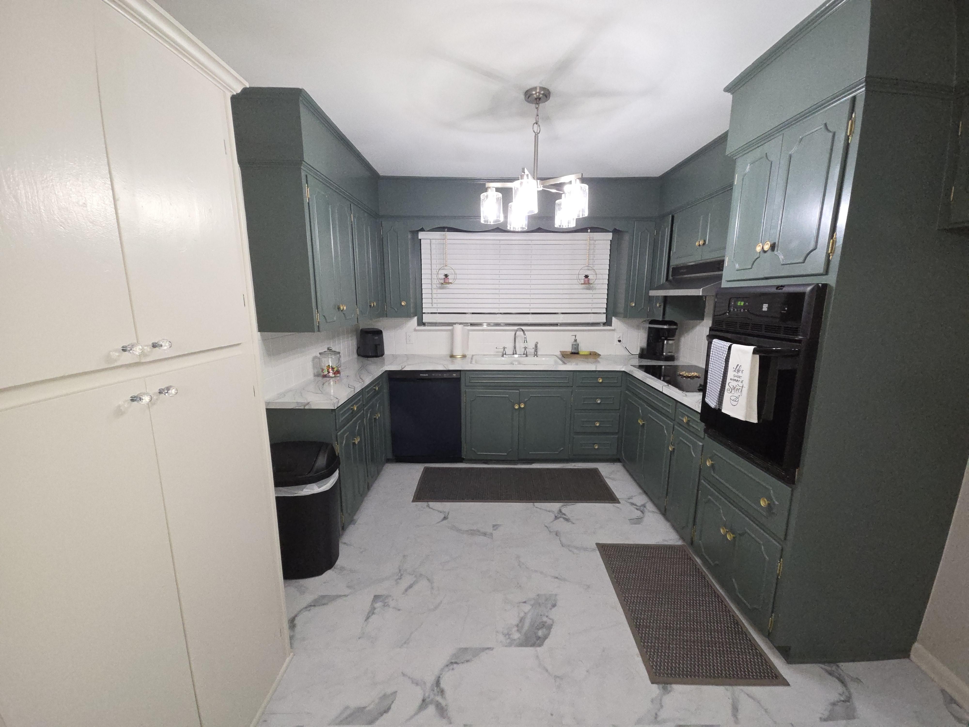 A sunlit dining room with crisp white walls, a rustic wooden table, and a large window, showing the smooth, even finish of a recent paint job.
