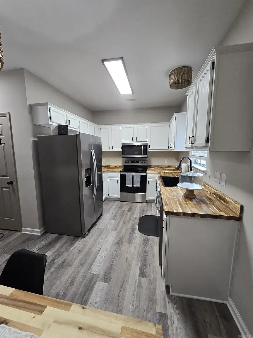 A sunlit dining room with crisp white walls, a rustic wooden table, and a large window, showing the smooth, even finish of a recent paint job.