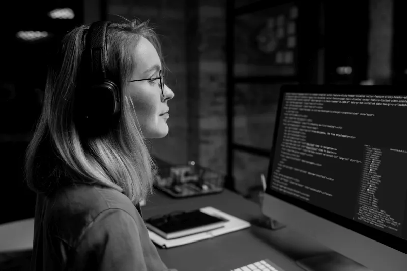 Woman working on a computer, looking at a screen with code