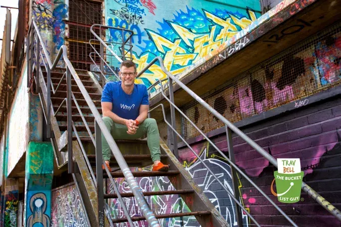 Trav Bell on metal stairs with colorful graffiti background