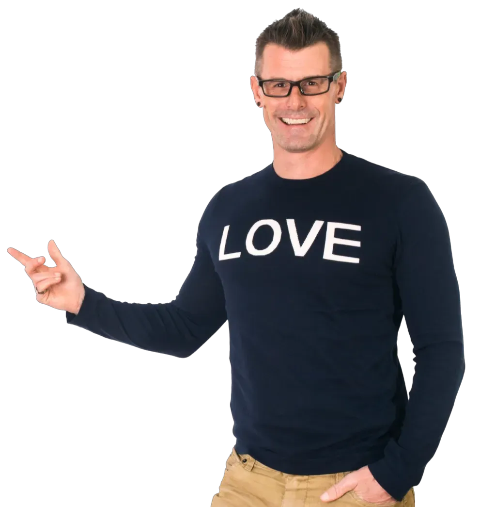 Trav Bell smiling and pointing while wearing a navy LOVE shirt