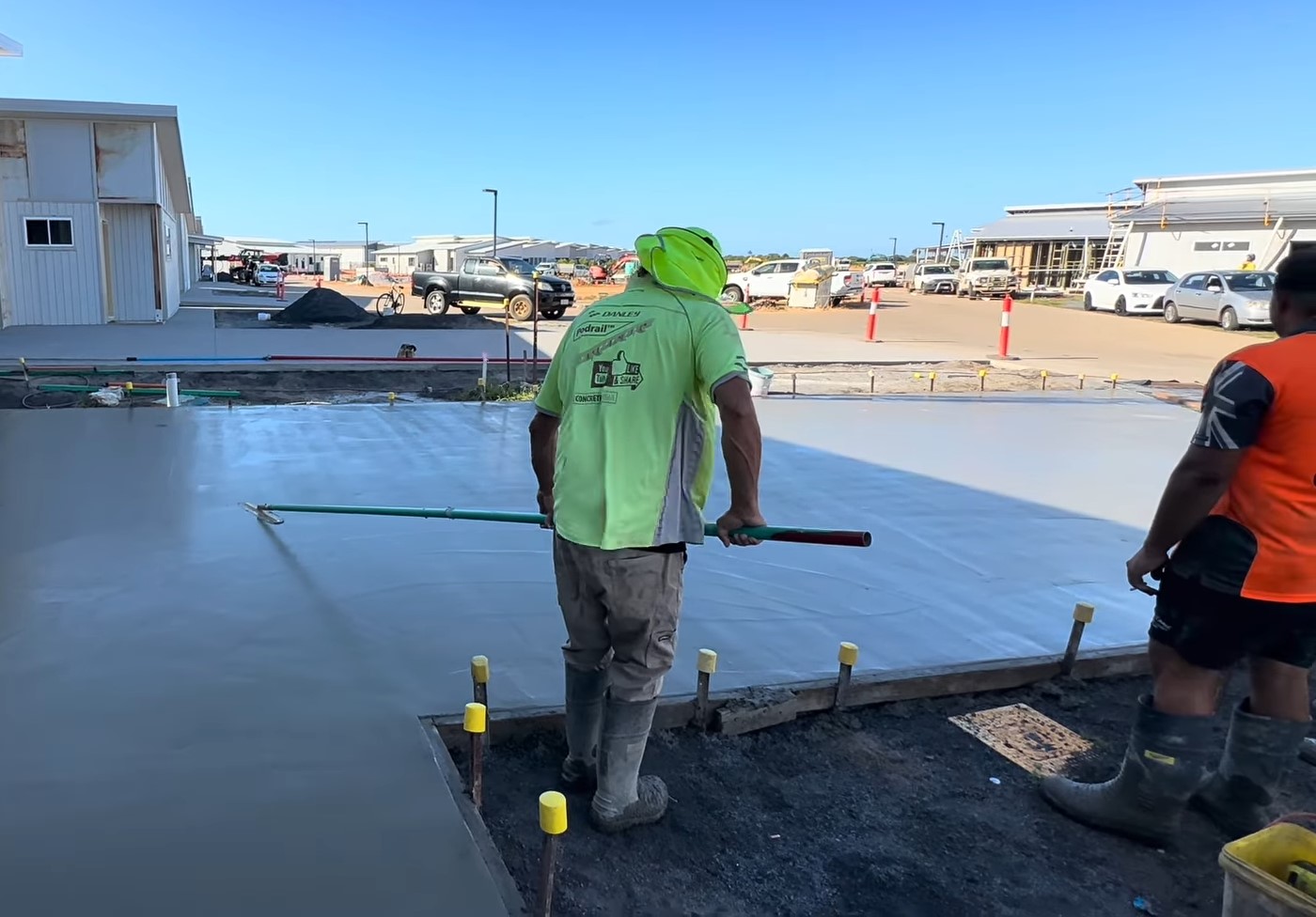 tradie using squiggly to spread concrete across driveway