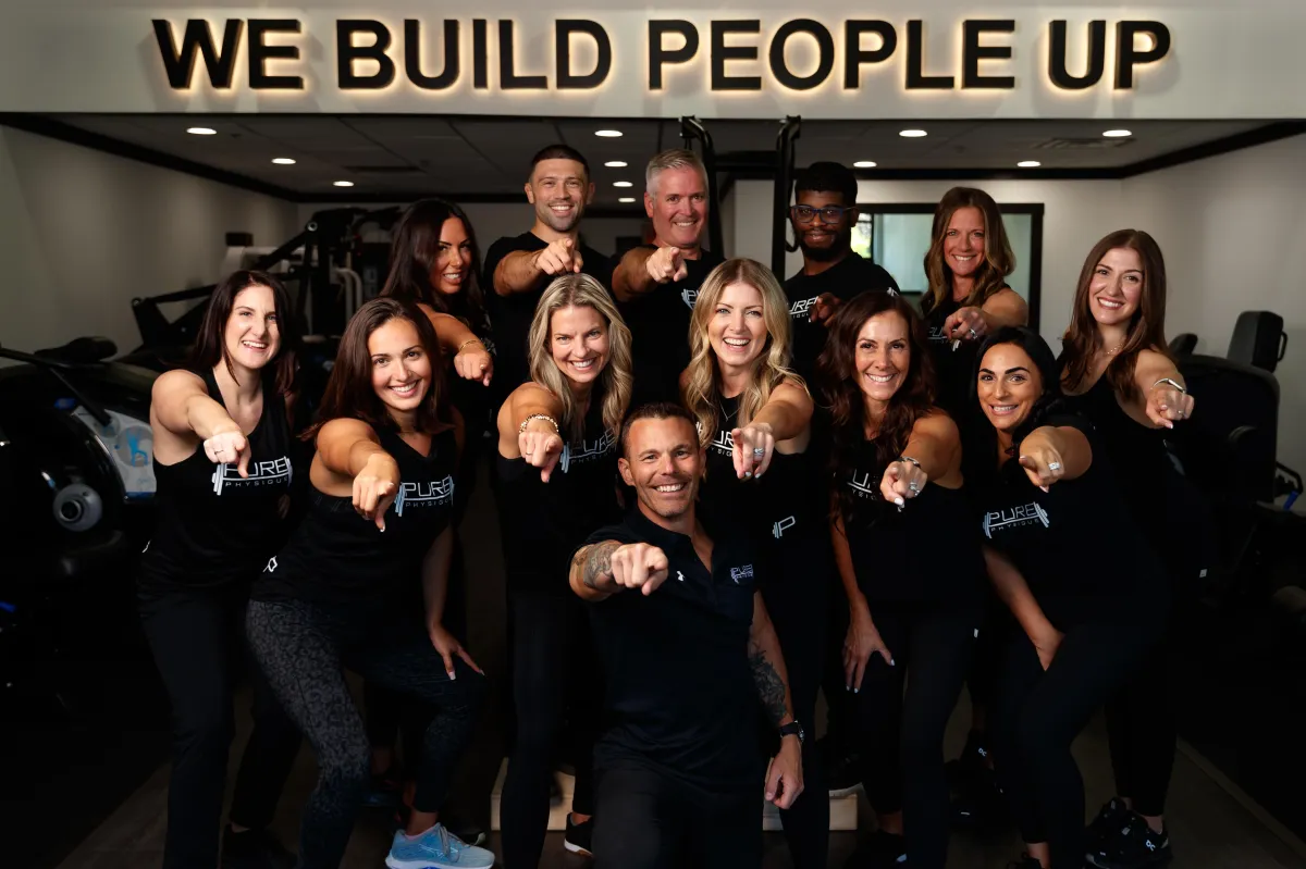 Man in hoodie boxing outdoors near fence.
