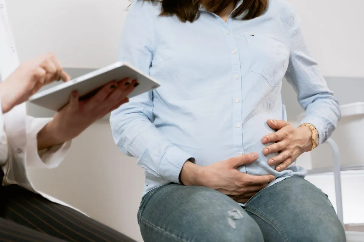 A pregnant woman in a chair, consulting with a professional