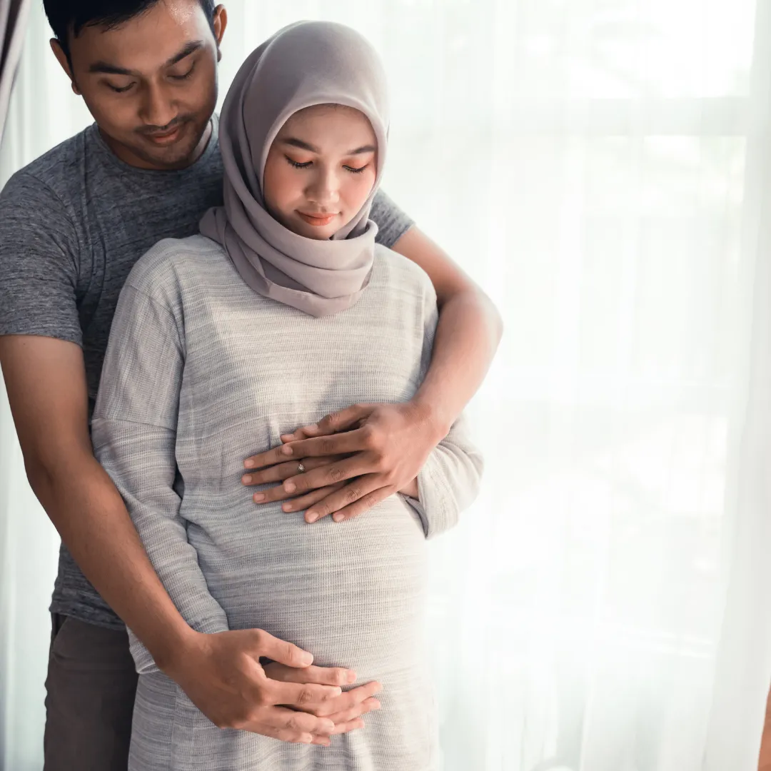 A pregnant woman and her partner, dressed in traditional Muslim attire, representing family and cultural identity in a moment of joy.