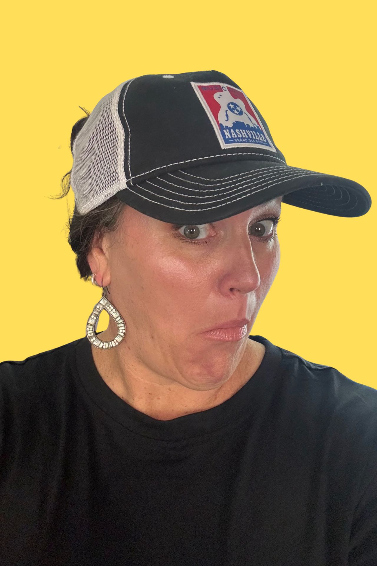 Carmen Ball making a playful surprised expression wearing a baseball cap