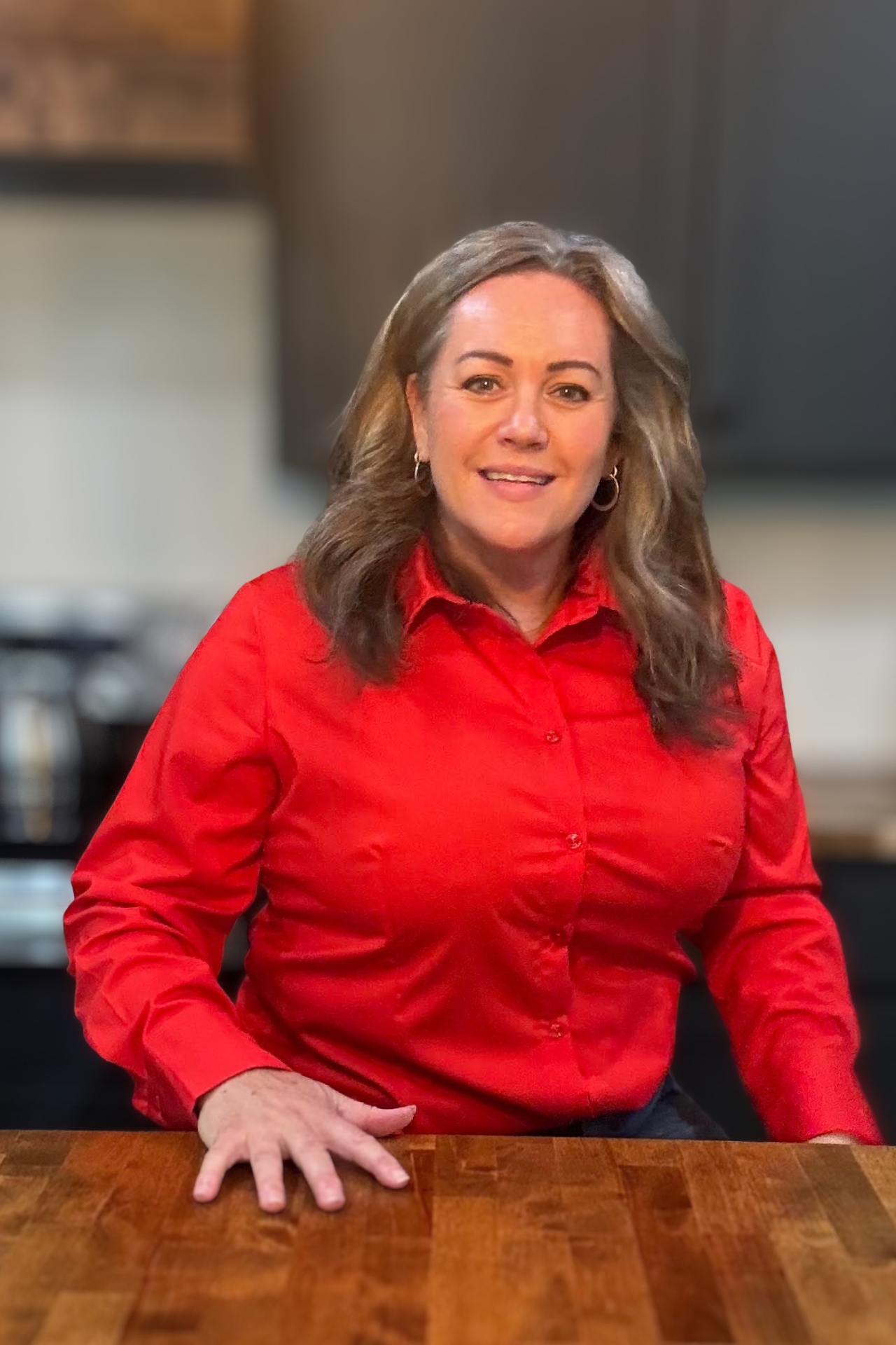 Carmen Ball smiling at a table in a red top