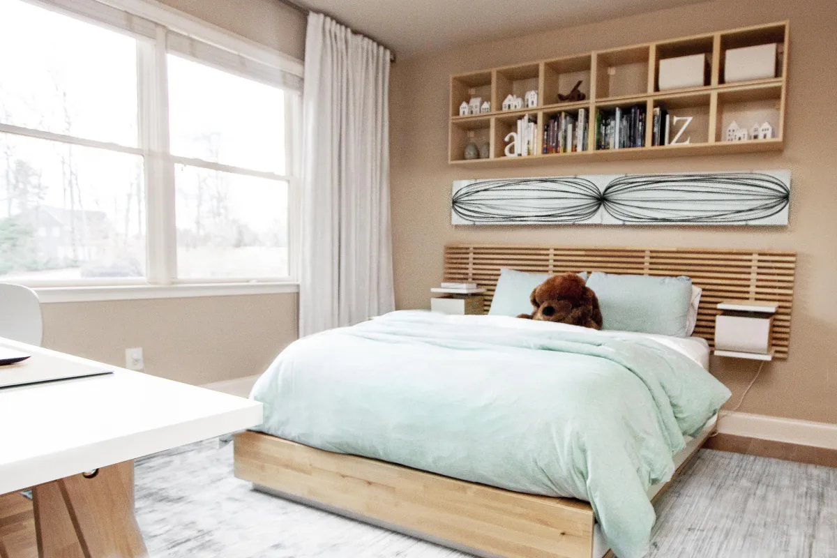 Boys’ room featuring a full size wooden bed with mint green bedding, wooden bookshelves, and black and white wall art.