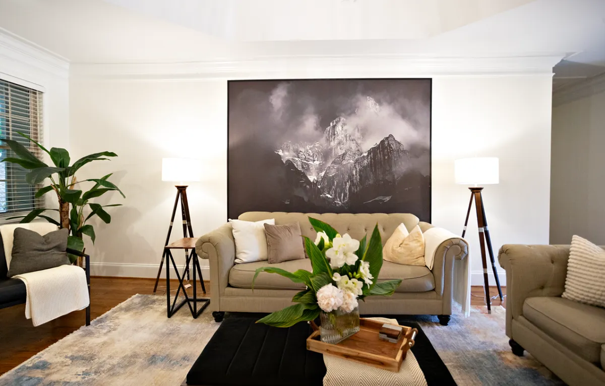 Traditional style living room featuring light brown linen couches, a black and white floor to ceiling canvas, and two wooden floor lamps.