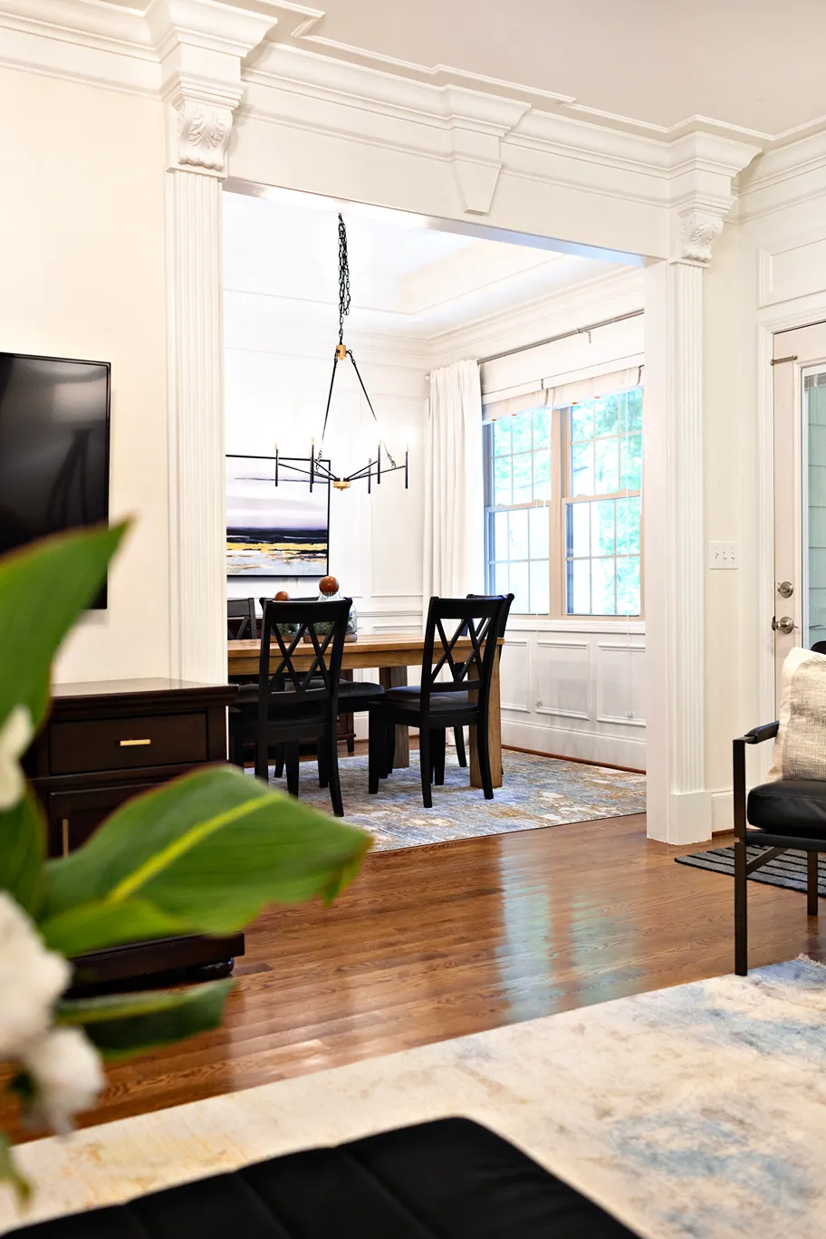 Entrance to a traditional style dining room from, showcasing large classic moldings and the earthy toned decor inside the dining room.