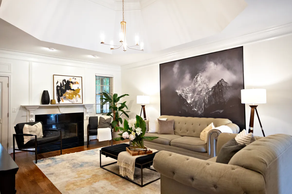 Traditional style living room showcasing a light brown linen sofa and loveseat, opposite of a molded fireplace and two black armchairs.