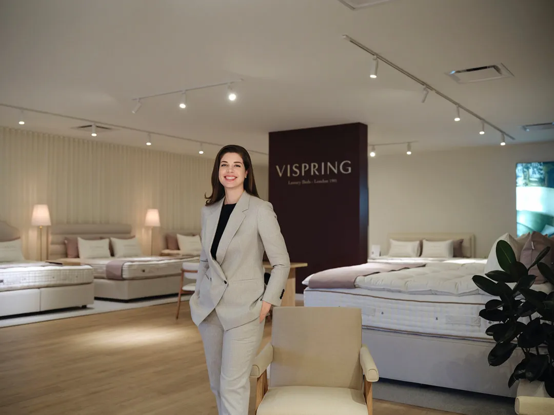 Woman in a pale suit standing in a bed showroom