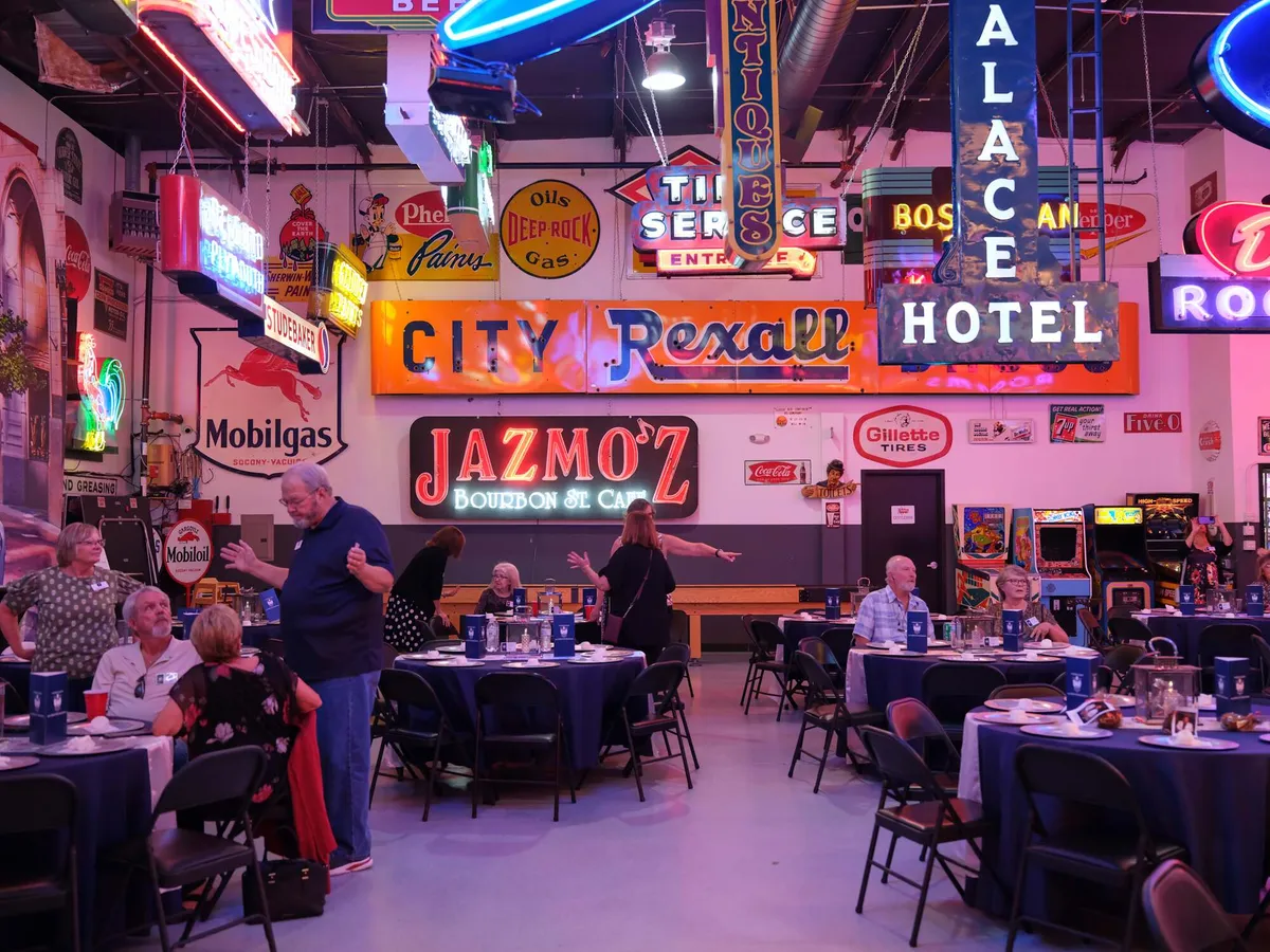 Guests seated at round tables in a neon lit hall at a hall of fame reunion dinner