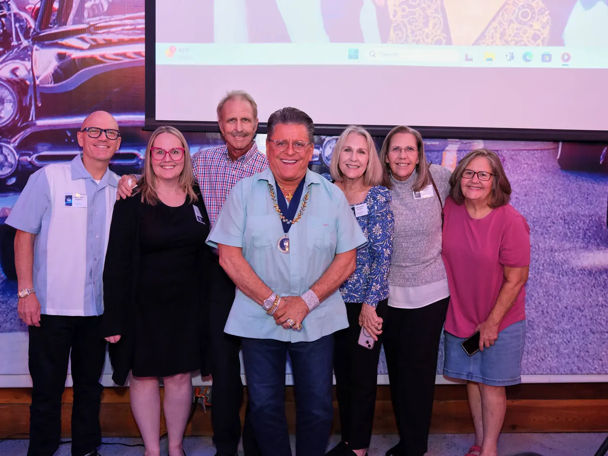 Group of guests posing together in front of a screen at a reunion event