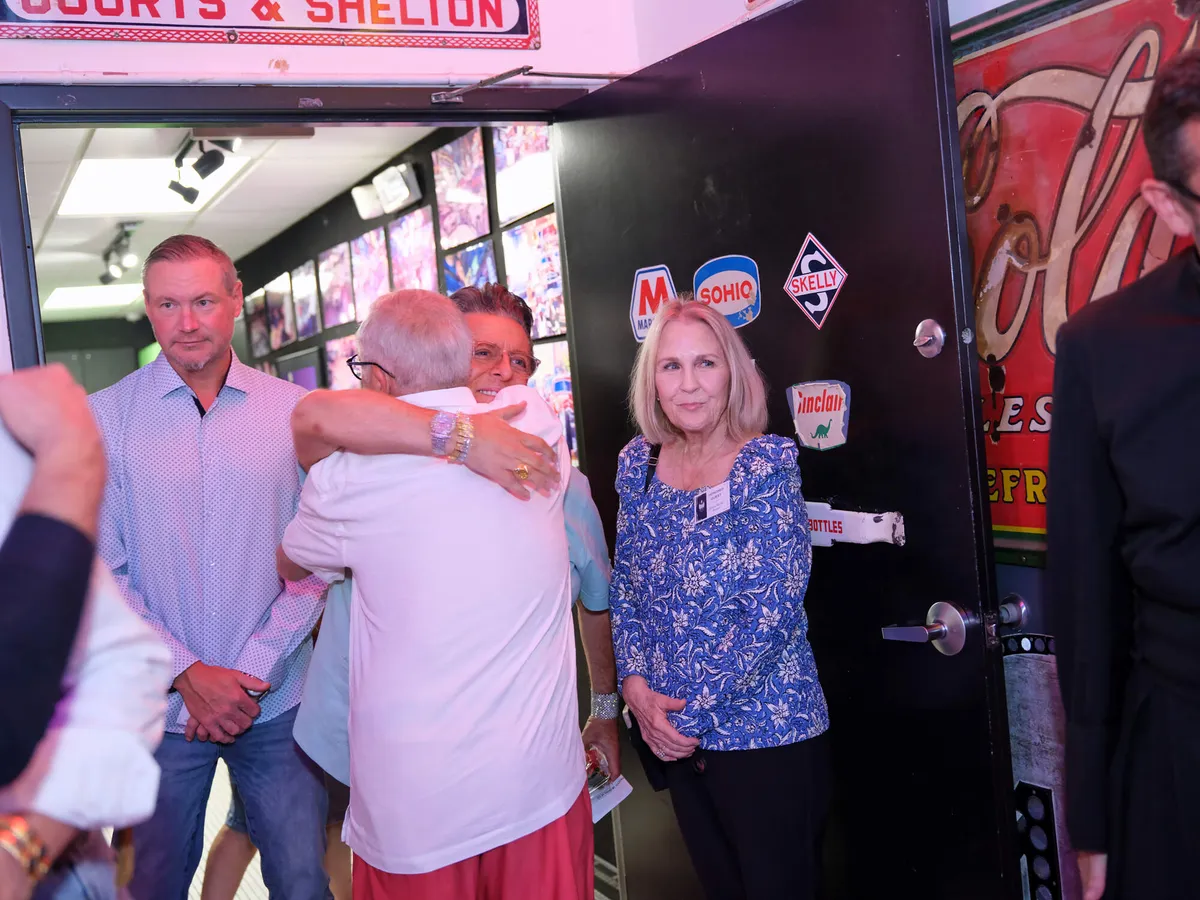 Guests greeting each other with a hug at the door of a reunion event