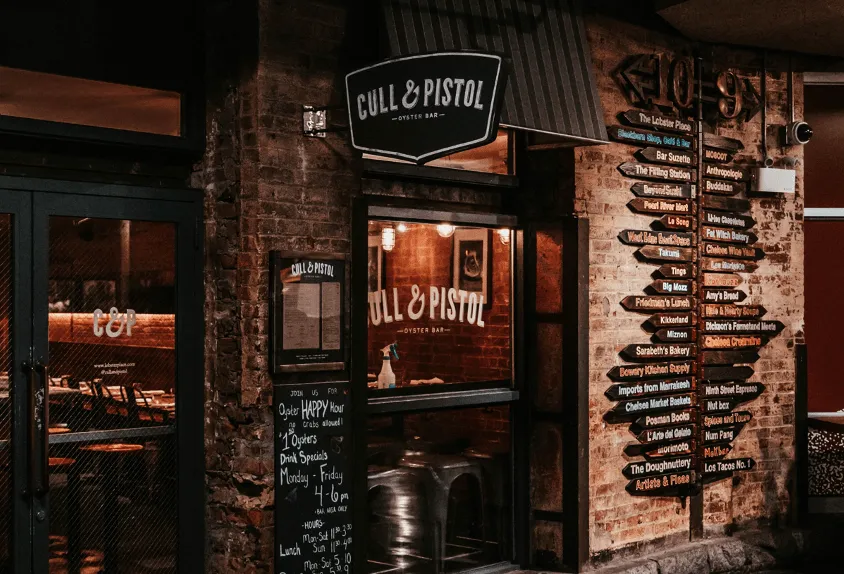 Chelsea Market vendor directory sign highlighting Cull & Pistol Oyster Bar, The Lobster Place, and over 20 restaurants and shops at this New York City food hall and retail destination.