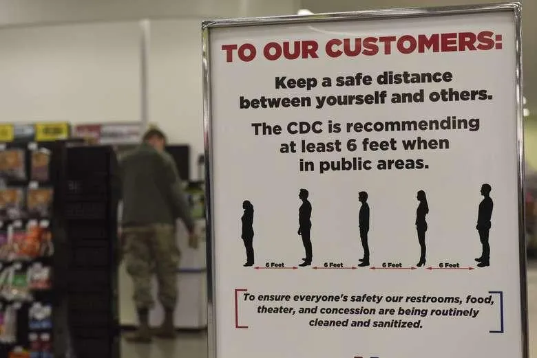 COVID-19 safety signage with the heading "To Our Customers: Preparing Your Business for the COVID-19 Pandemic." Text indicates CDC recommends at least 6 feet between yourself and others in public areas, and that restrooms, food, theater, and concession areas are being routinely cleaned and sanitized