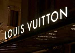 Louis Vuitton store exterior with large, backlit channel letter signage at night.